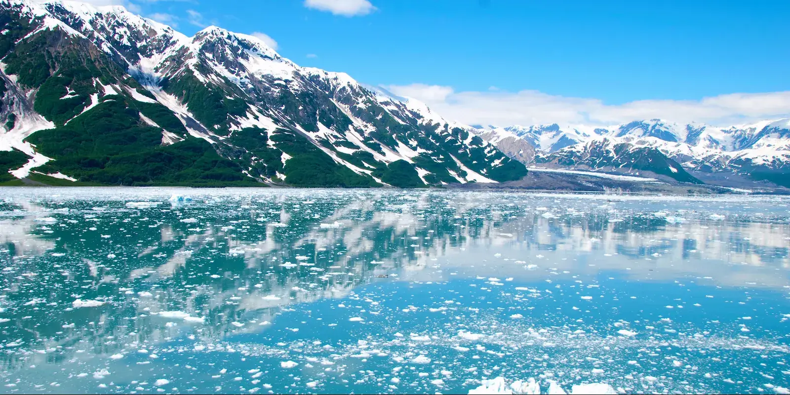 Snow-capped mountains reflected in a glacial lake with floating ice